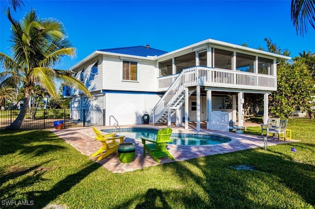 rear view of property featuring a lawn, a fenced in pool, a sunroom, and a patio area