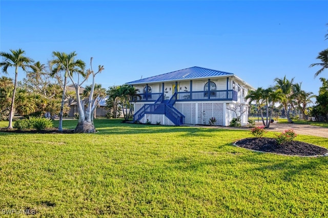 3131 Twin Lakes Ln, Sanibel, FL 33957 - view of front of home with a standing seam roof, covered porch, metal roof, a front yard, and stairs