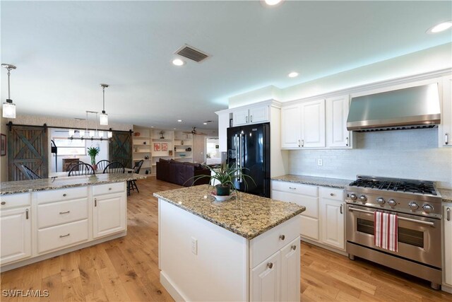 3131 Twin Lakes Ln, Sanibel, FL 33957 - kitchen featuring stainless steel stove, a center island, black refrigerator with ice dispenser, visible vents, and wall chimney exhaust hood