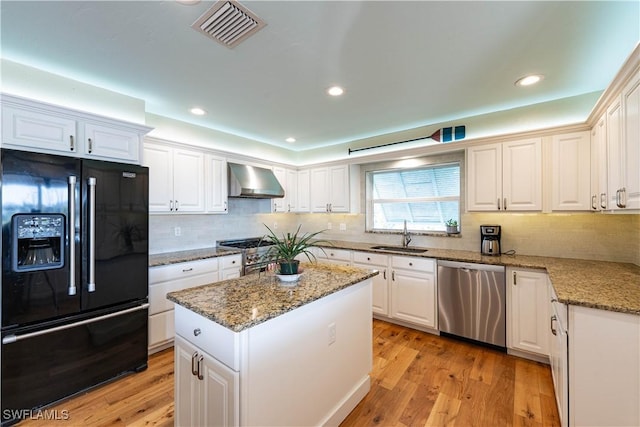 3131 Twin Lakes Ln, Sanibel, FL 33957 - kitchen featuring visible vents, white cabinets, wall chimney exhaust hood, a sink, and high quality appliances