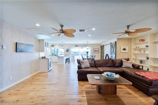 3131 Twin Lakes Ln, Sanibel, FL 33957 - living area featuring light wood-style floors, wallpapered walls, ceiling fan, and a barn door