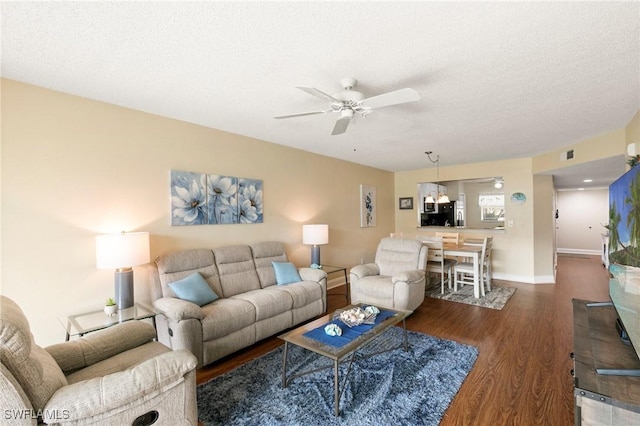 living room with ceiling fan, dark hardwood / wood-style flooring, and a textured ceiling