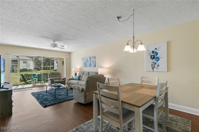 dining area with dark wood-type flooring, ceiling fan with notable chandelier, and a textured ceiling