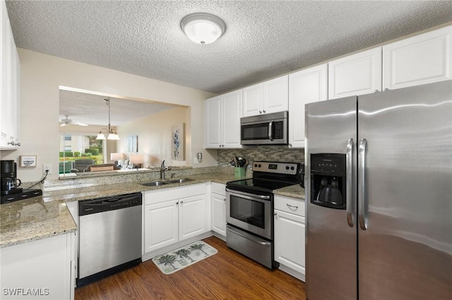 kitchen with sink, white cabinetry, light stone counters, appliances with stainless steel finishes, and kitchen peninsula