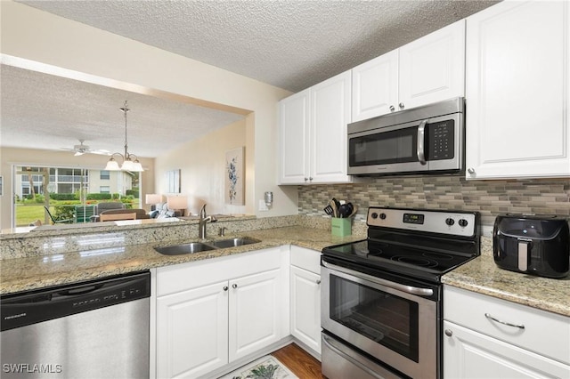 kitchen with tasteful backsplash, sink, white cabinets, light stone counters, and stainless steel appliances