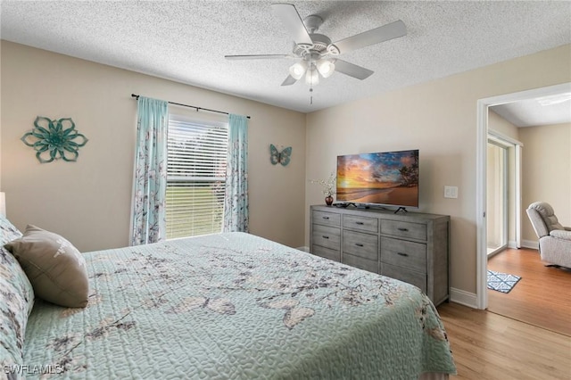 bedroom with ceiling fan, light hardwood / wood-style flooring, and a textured ceiling