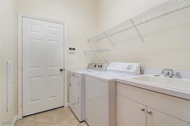 washroom featuring cabinets, light tile patterned floors, washer and clothes dryer, and sink