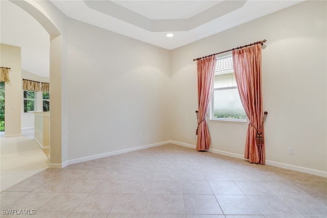 empty room with light tile patterned floors and a raised ceiling