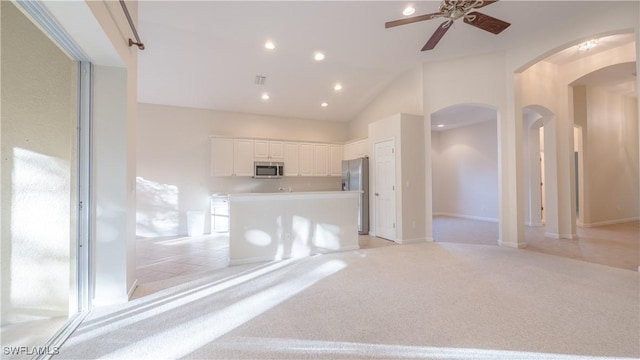 unfurnished living room with light carpet, high vaulted ceiling, and ceiling fan