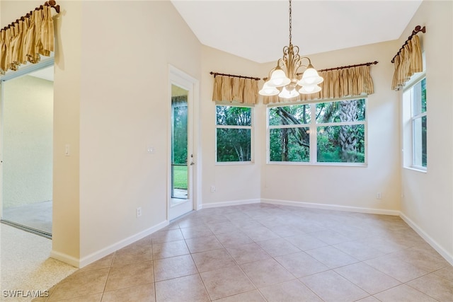 tiled spare room with an inviting chandelier