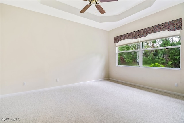 spare room featuring carpet flooring, ceiling fan, and a raised ceiling