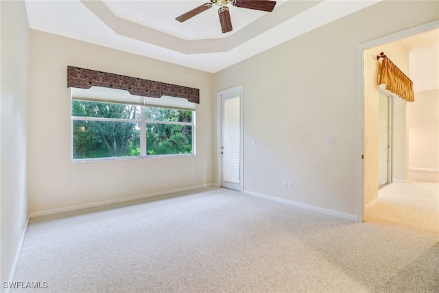 carpeted empty room featuring ceiling fan and a raised ceiling