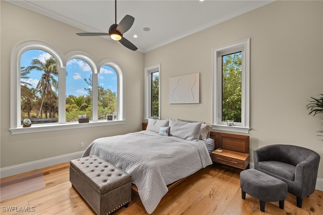 bedroom featuring ceiling fan, ornamental molding, multiple windows, and light wood-type flooring