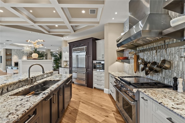 330 Cowry Ct, Sanibel, FL 33957 - kitchen with light stone countertops, a sink, premium appliances, wall chimney range hood, and coffered ceiling