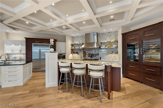 330 Cowry Ct, Sanibel, FL 33957 - kitchen featuring wall chimney range hood, a spacious island, appliances with stainless steel finishes, and light wood-style flooring