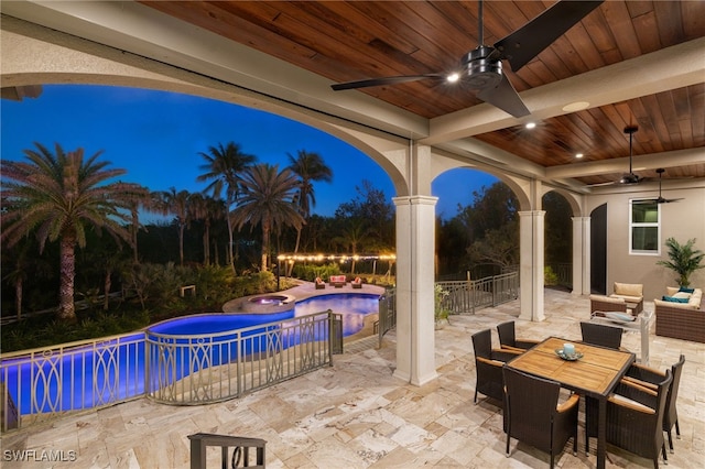 patio at night with a swimming pool with hot tub, outdoor lounge area, and ceiling fan