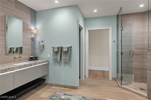 bathroom featuring a shower with door and vanity