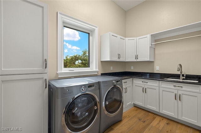 laundry area featuring cabinets, independent washer and dryer, sink, and light hardwood / wood-style flooring