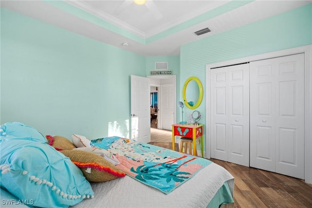 bedroom with wood finished floors, visible vents, a ceiling fan, a closet, and a raised ceiling