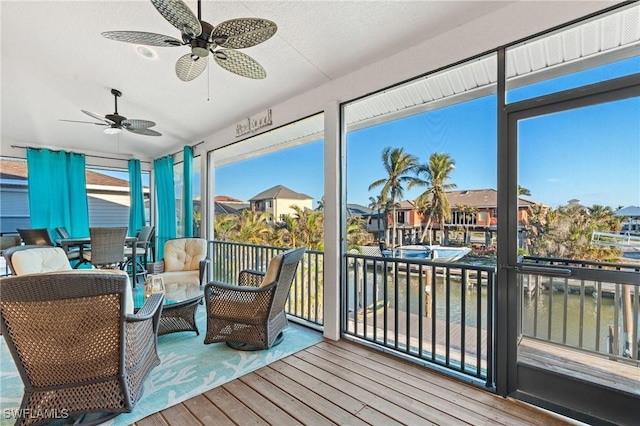 sunroom with ceiling fan, plenty of natural light, and a residential view