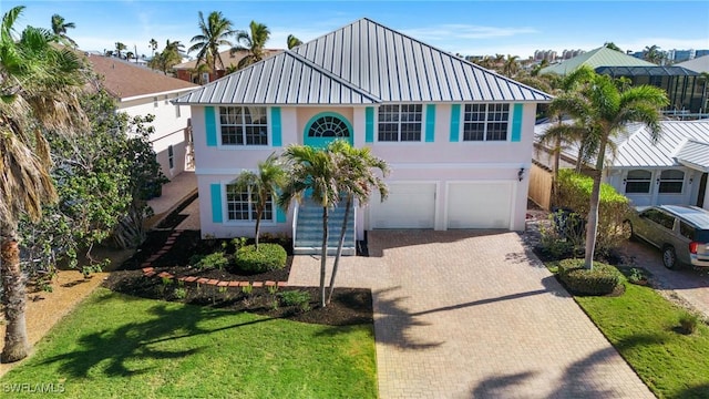 view of front facade featuring metal roof, a garage, decorative driveway, stucco siding, and a front lawn