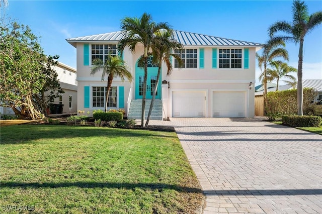 view of front of home with a garage, stucco siding, metal roof, decorative driveway, and a front yard