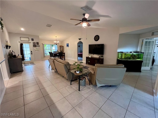 tiled living room with ceiling fan with notable chandelier