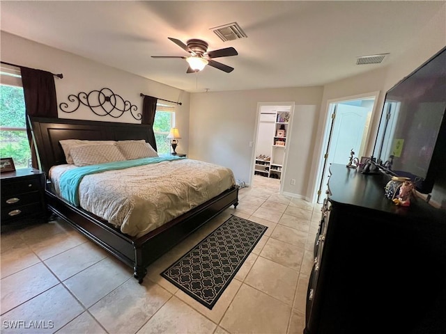 tiled bedroom with a spacious closet and ceiling fan