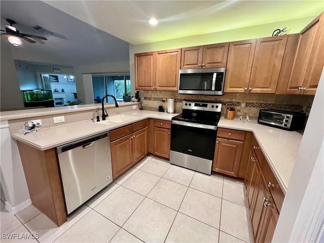 kitchen with backsplash, kitchen peninsula, sink, light tile patterned flooring, and appliances with stainless steel finishes