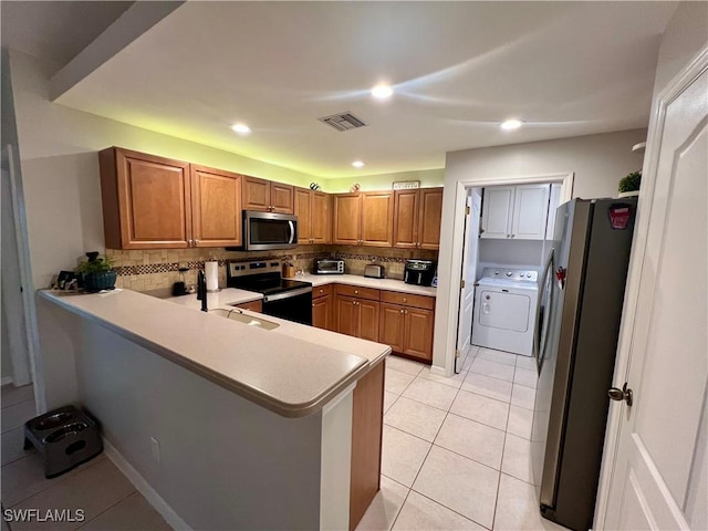 kitchen with tasteful backsplash, washer / clothes dryer, kitchen peninsula, sink, and appliances with stainless steel finishes