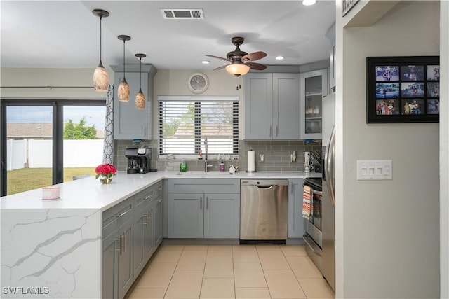 kitchen with decorative backsplash, appliances with stainless steel finishes, gray cabinets, and pendant lighting