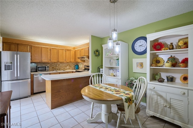 kitchen featuring light tile patterned floors, appliances with stainless steel finishes, backsplash, pendant lighting, and sink