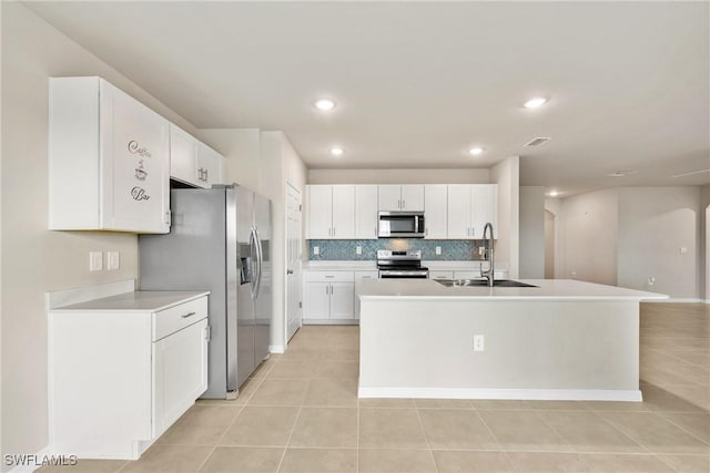 kitchen featuring a kitchen island with sink, light tile patterned floors, sink, white cabinets, and stainless steel appliances