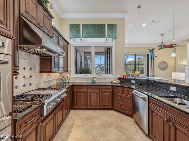 kitchen with appliances with stainless steel finishes, hanging light fixtures, tasteful backsplash, ornamental molding, and dark stone counters