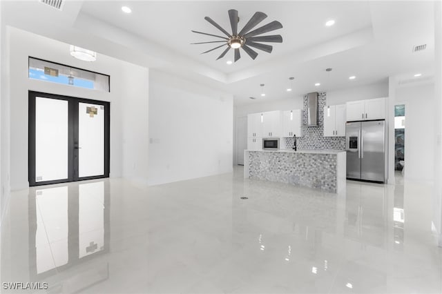 unfurnished living room featuring french doors, sink, and a tray ceiling