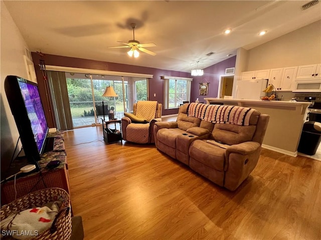 living room with light wood-type flooring, lofted ceiling, and ceiling fan with notable chandelier