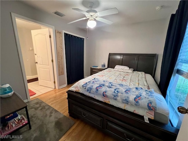 bedroom featuring ceiling fan, light hardwood / wood-style flooring, and ensuite bath