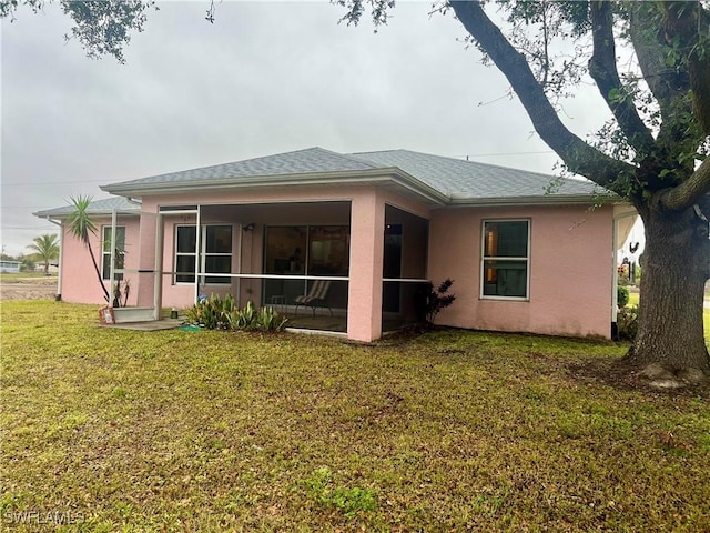 rear view of property featuring a yard and a sunroom