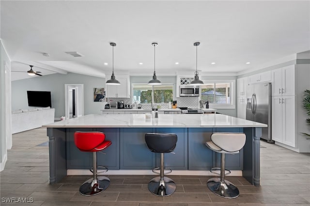 kitchen with pendant lighting, white cabinetry, a large island, and appliances with stainless steel finishes