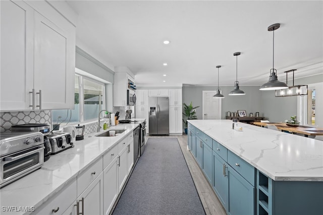 kitchen featuring decorative light fixtures, white cabinetry, a large island, and appliances with stainless steel finishes