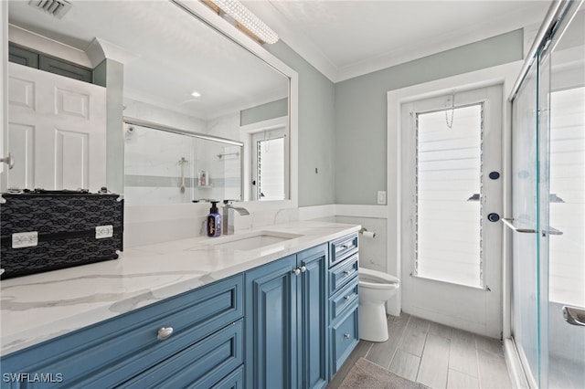 bathroom with ornamental molding, a shower with door, toilet, and vanity