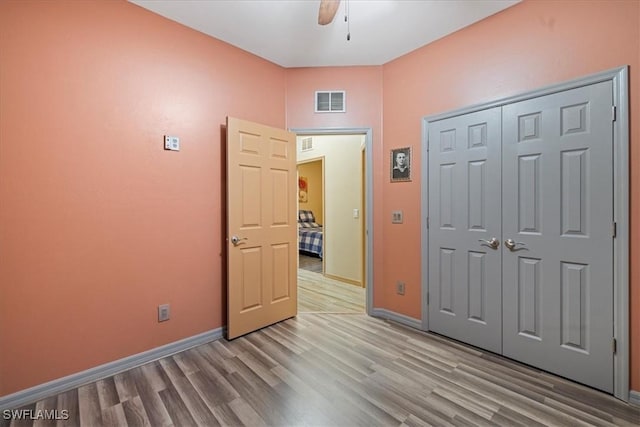 unfurnished bedroom with ceiling fan, a closet, and light hardwood / wood-style flooring