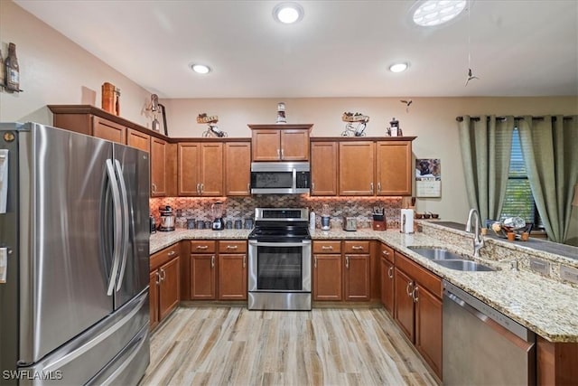 kitchen featuring light hardwood / wood-style floors, sink, kitchen peninsula, stainless steel appliances, and light stone counters