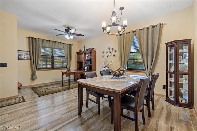 dining area with light wood-type flooring and ceiling fan with notable chandelier