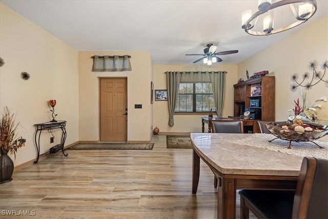 dining area with light wood-type flooring and ceiling fan with notable chandelier