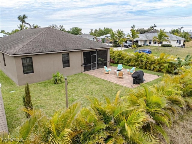 back of property with a yard, a sunroom, and a patio