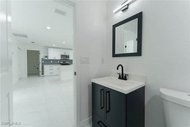 bathroom featuring toilet, vanity, and decorative backsplash