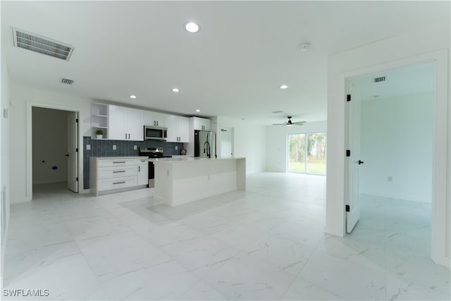 kitchen with a kitchen island, white cabinetry, stainless steel appliances, backsplash, and ceiling fan