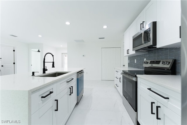 kitchen featuring sink, white cabinets, a center island with sink, and stainless steel appliances