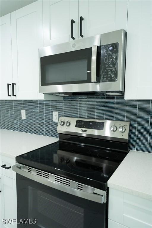 kitchen with decorative backsplash, white cabinets, and appliances with stainless steel finishes